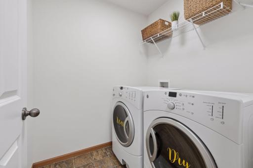 The laundry is in a separate room on the upper level with wall shelving.
