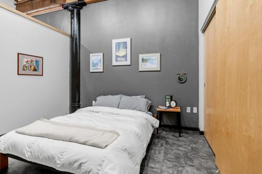 Primary bedroom with expansive reach-in closet, featuring an organization system. Exposed piping and 8' privacy wall allow for character and personality to the space.