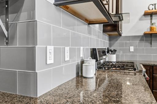 Tiled backsplash of glass subway and granite counters.