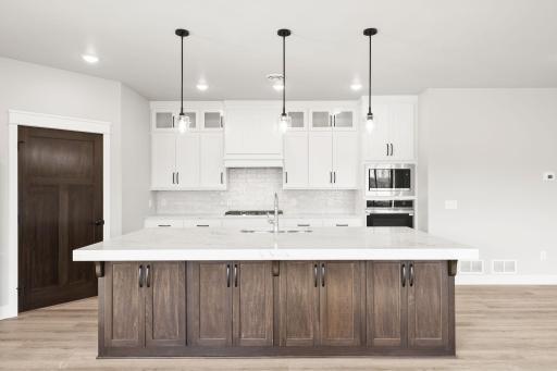 The large kitchen island with quartz countertops offers plenty of prep space and room for stools, making it perfect for both cooking and casual gatherings.