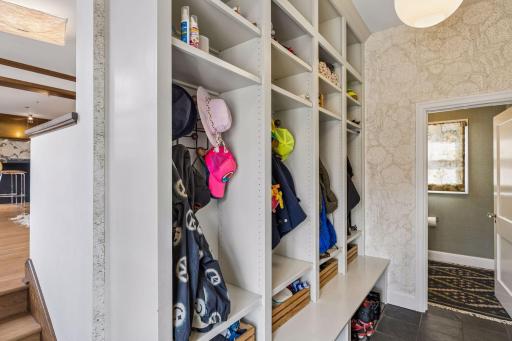 Main level mudroom with stone tile floors and an adjacent powder room. This is the second of two main level powder rooms. Direct access from the mudroom to the 2.5 car attached garage.