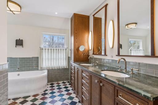 Masterfully renovated primary bath with marble counters and tile, designer finishes, luxury fixtures, and plentiful storage.