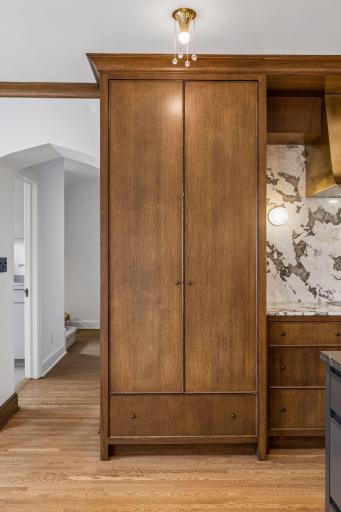 Retractable cabinet doors conceal Wolf double ovens and storage. A main level laundry room is located in a hall just off of the kitchen.