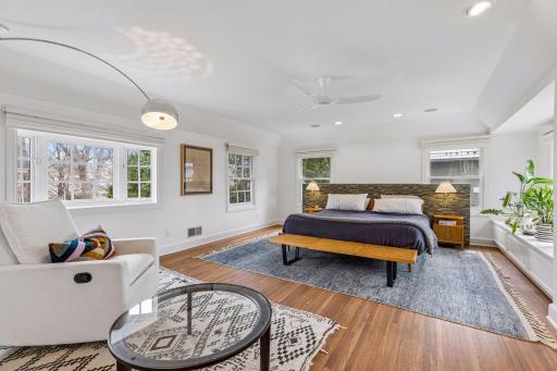 Spacious primary bedroom with three sides of windows and custom electronic blinds.