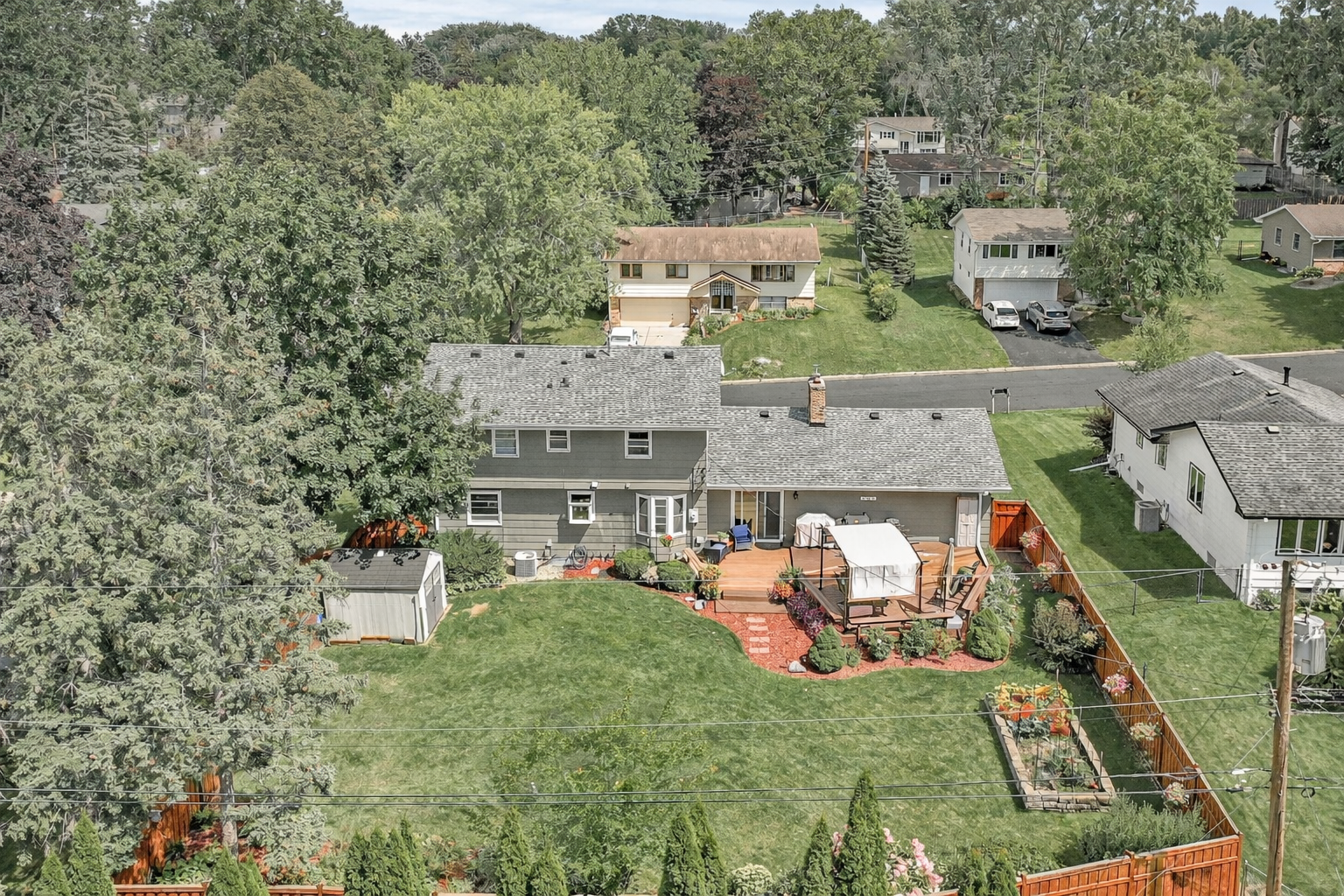 The backyard is a true "fenced-in oasis," featuring a private deck, manicured gardens, and a convenient extra shed for the garden enthusiast.