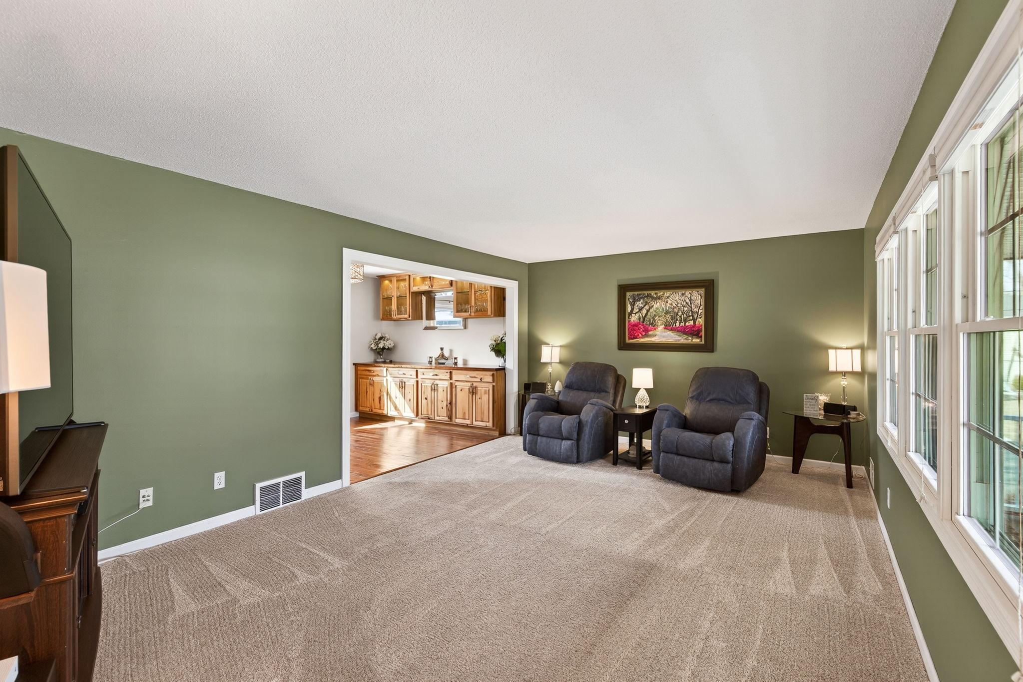 Sun-drenched formal living room featuring large windows and elegant transitions to the dining area.