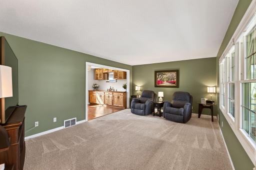 Sun-drenched formal living room featuring large windows and elegant transitions to the dining area.