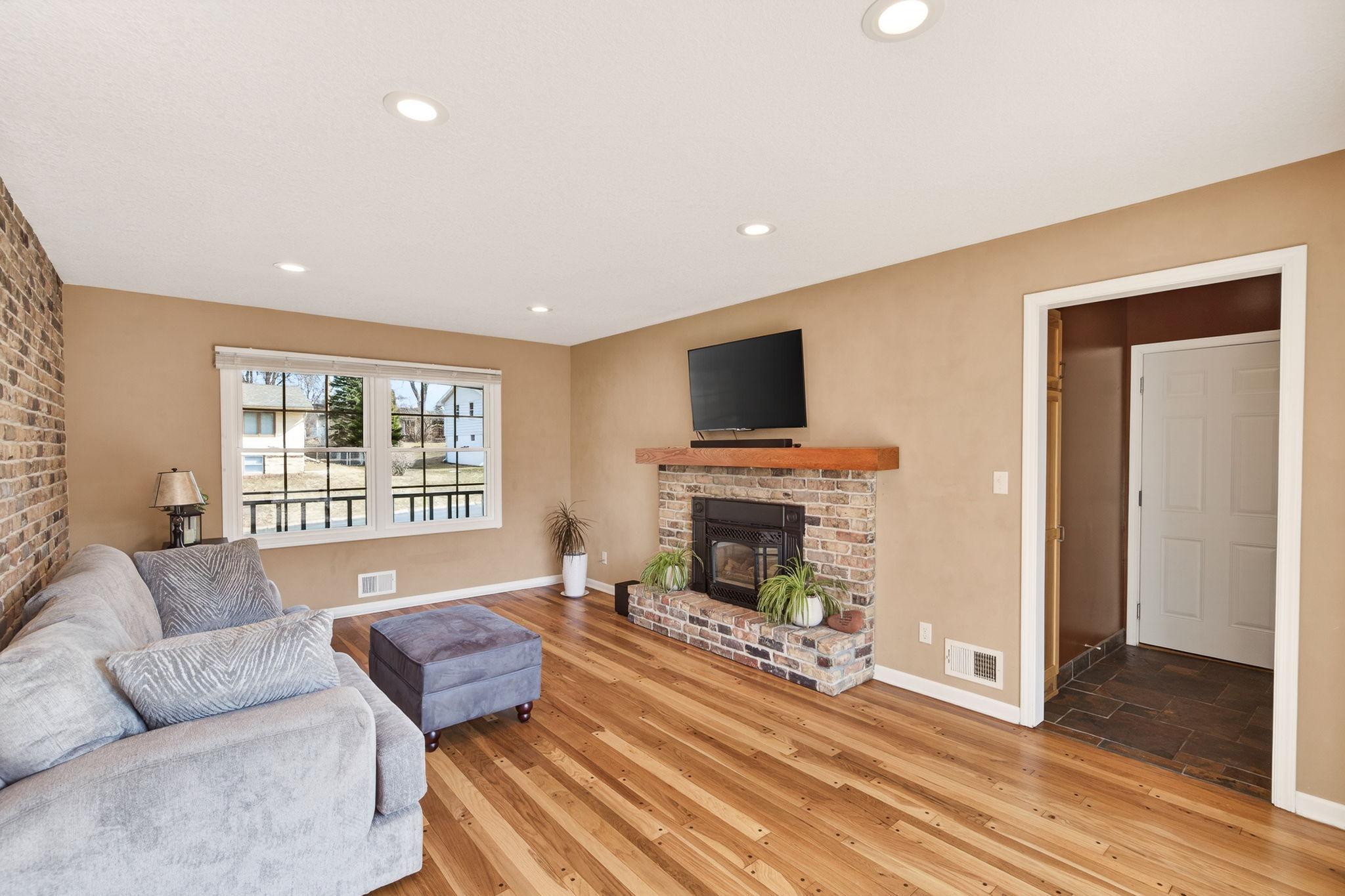 Warmth from every angle. Freshly refinished hardwoods glow under the ambiance of the gas fireplace, while the full-height brick wall adds a touch of mid-century modern soul.