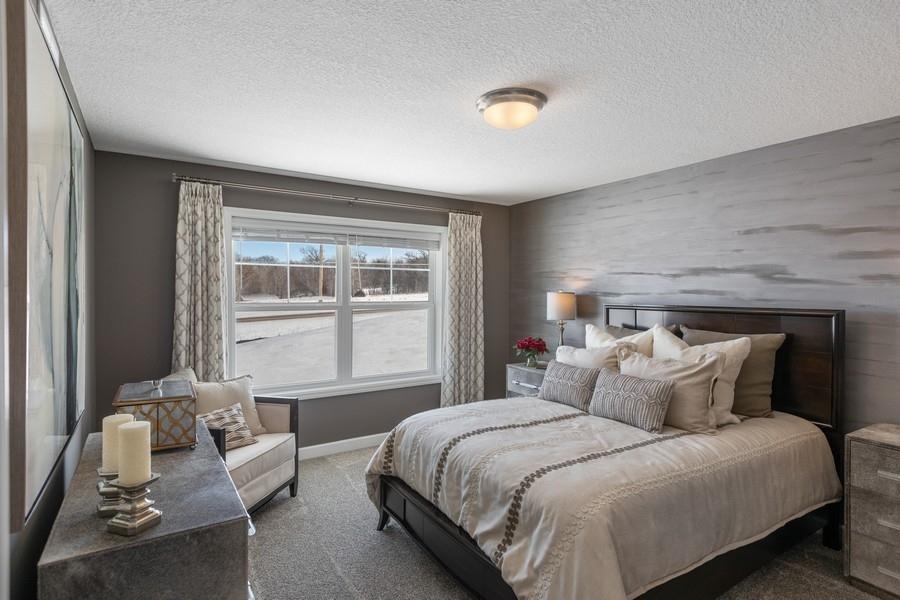 (Photo of decorated model, actual home's finishes will vary) Spacious owner's suite with large window, walk-in closet, and private bathroom.