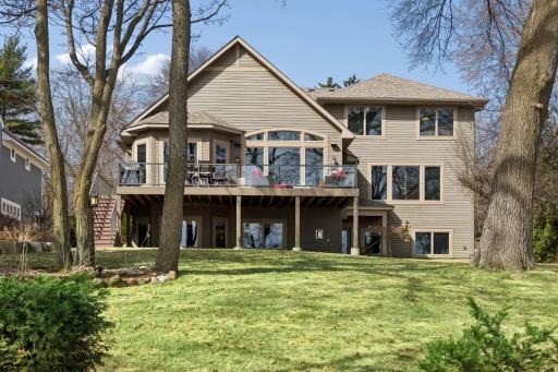 The back of the home is designed to take advantage of the setting, with expansive windows and a large deck that extends to the yard, offering space for dining, grilling, and outdoor seating.