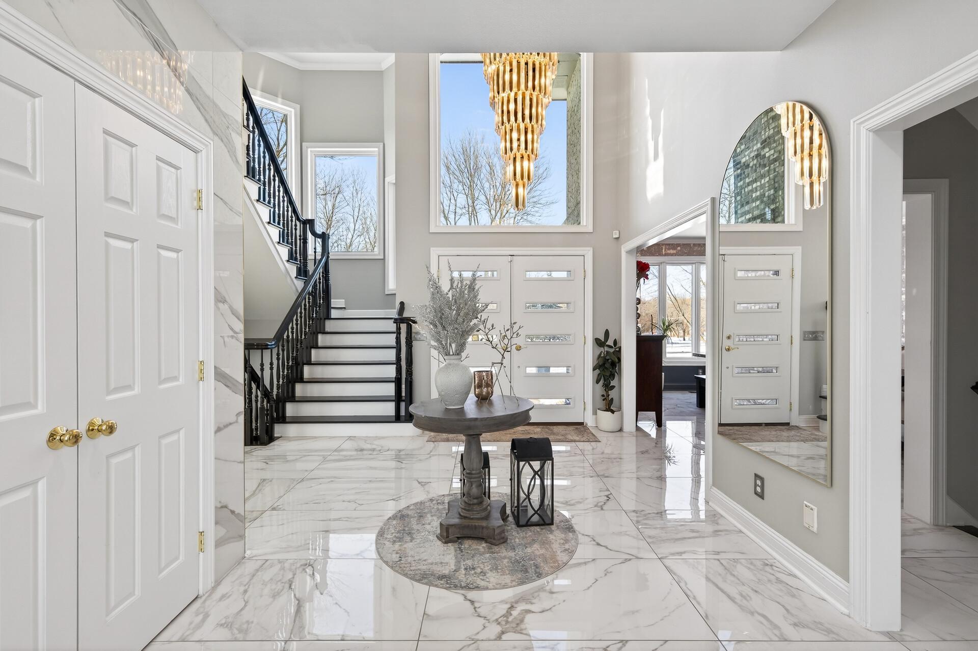 Upon entering the grand foyer, you’re welcomed by soaring 18-foot ceilings, a stunning chandelier, and marble floors that flow seamlessly throughout the main level.