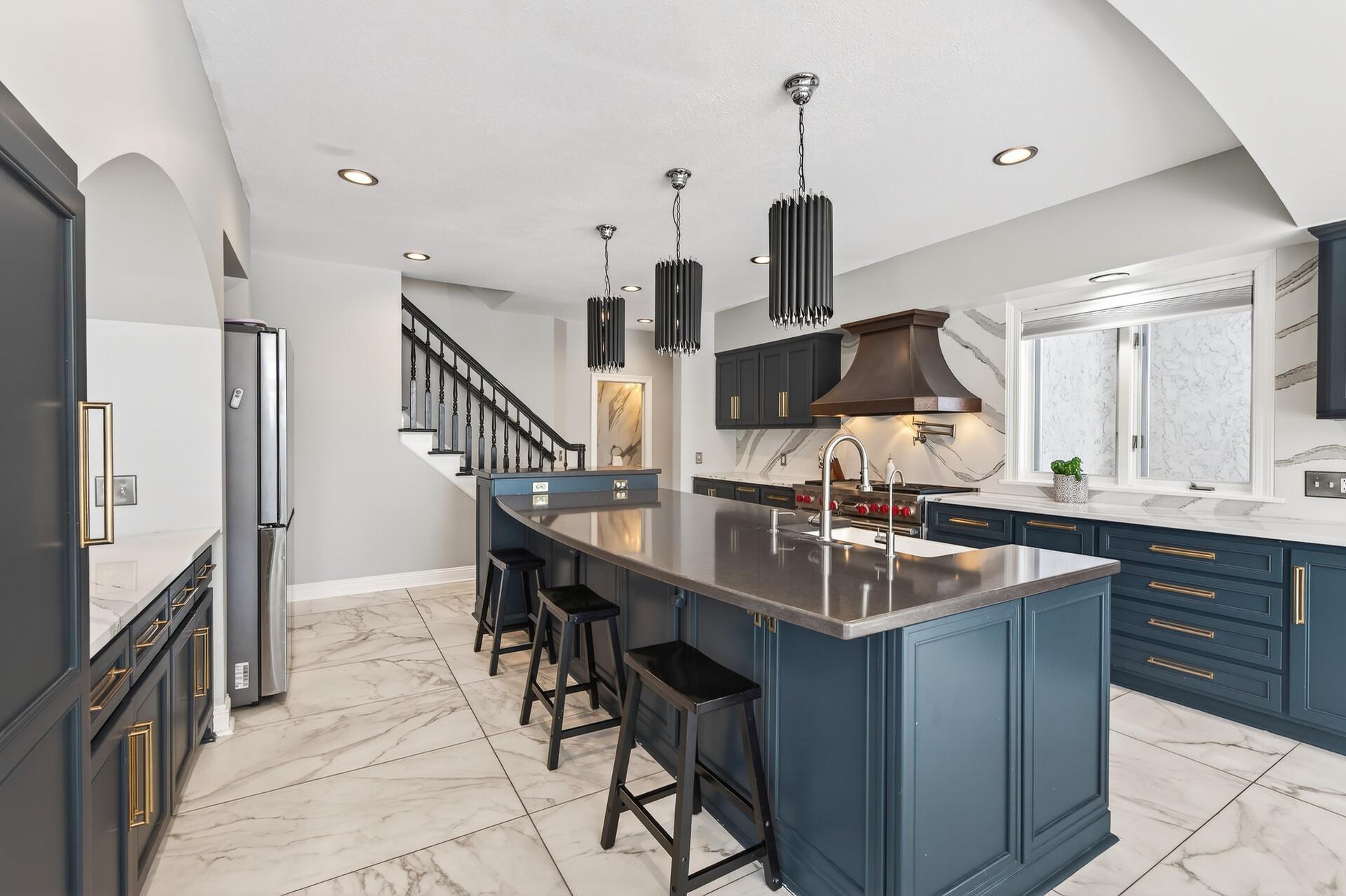 The kitchen is a chef’s dream, featuring an abundance of quartz and marble countertops, including an expansive center island with unique pendant lighting and breakfast bar seating.