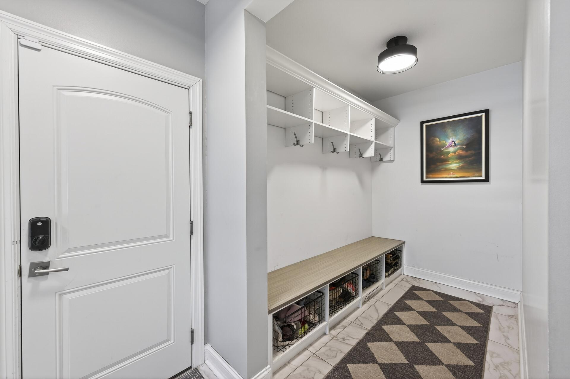 Completing the main level is a mudroom with cubbies and lockers, providing easy access to the spacious three-car garage, which features wall hooks, a dedicated workstation, and cabinetry for organized storage.