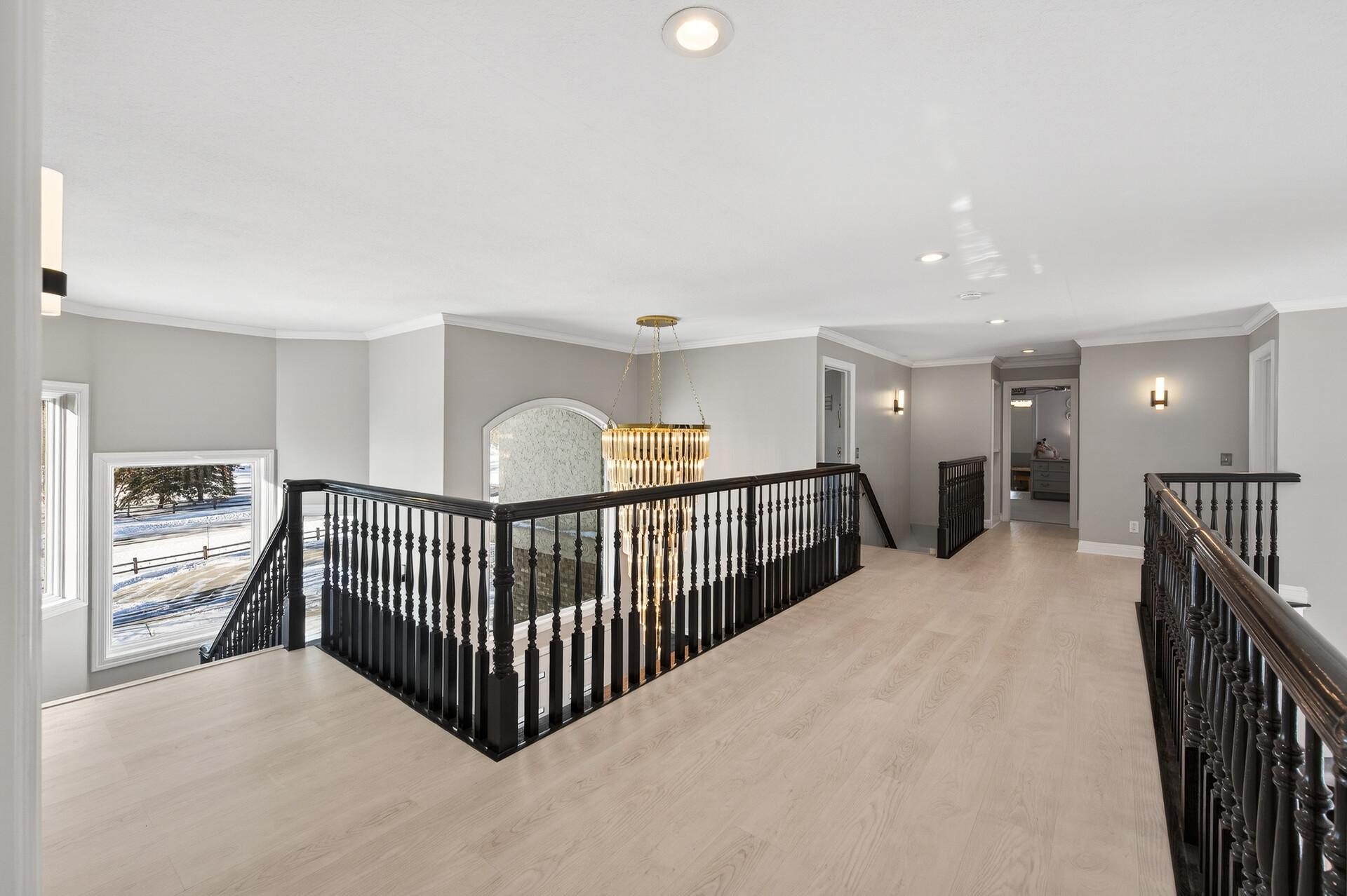 An open catwalk overlooks the main living area and leads to the opposite wing of the upper level, where the remaining three bedrooms are located.