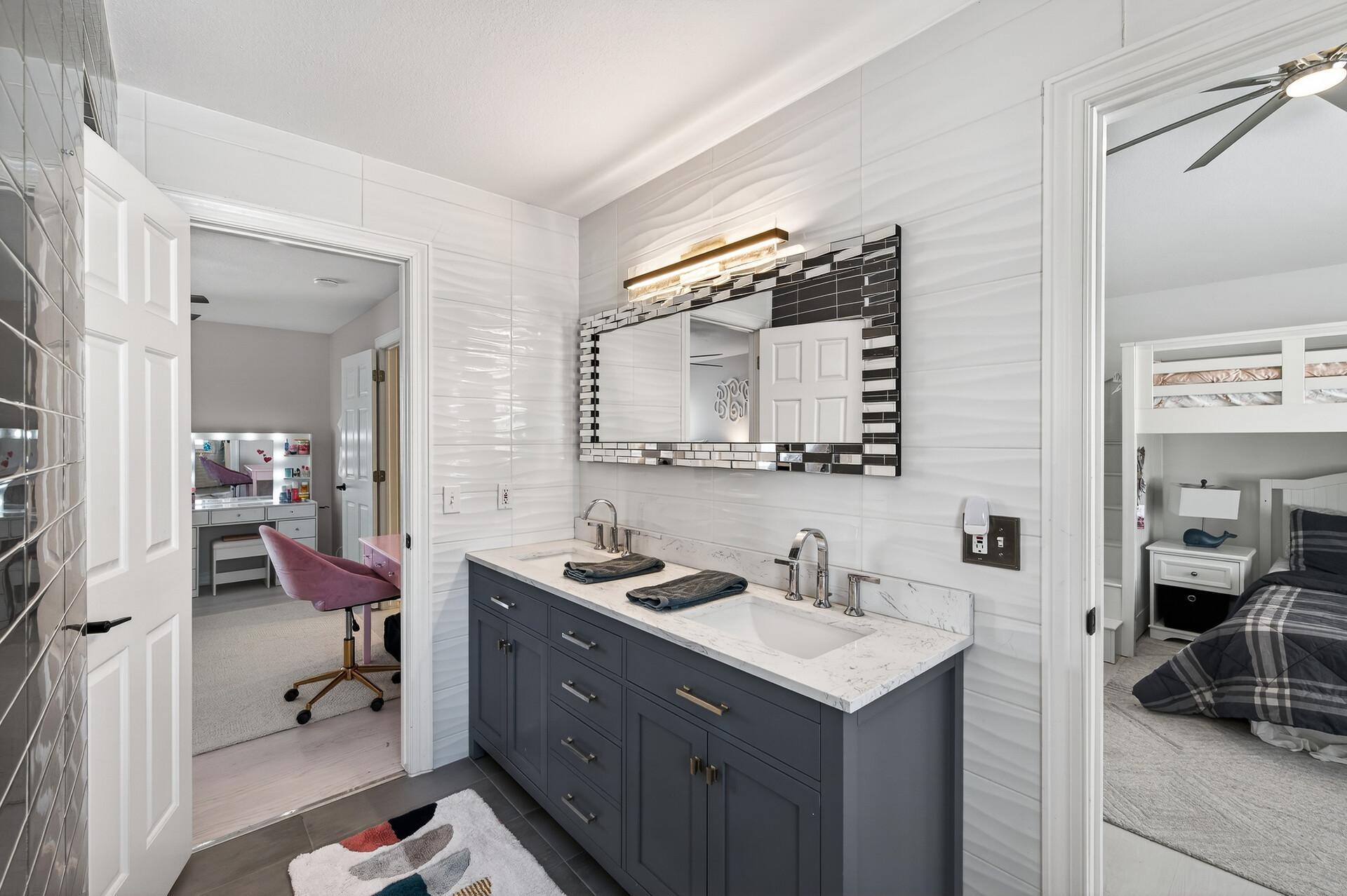 Bedroom two shares a well-appointed three-quarter Jack-and-Jill bathroom with bedroom three, offering tile flooring, a walk-in shower, tiled walls, and a double vanity.