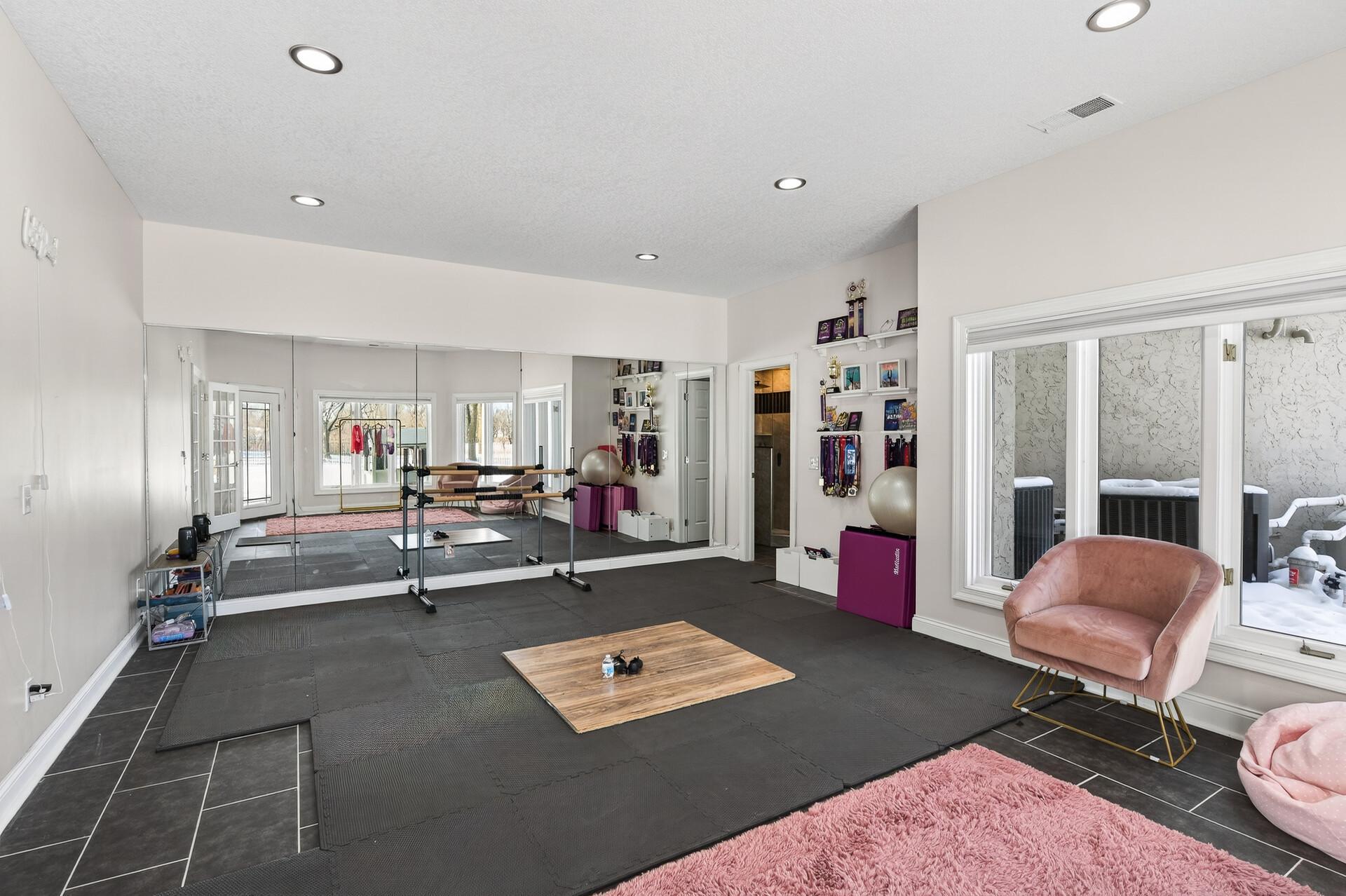 Also adjacent to the family room is a large exercise room featuring glass French doors, a mirrored wall, and direct access to the patio and pool.
