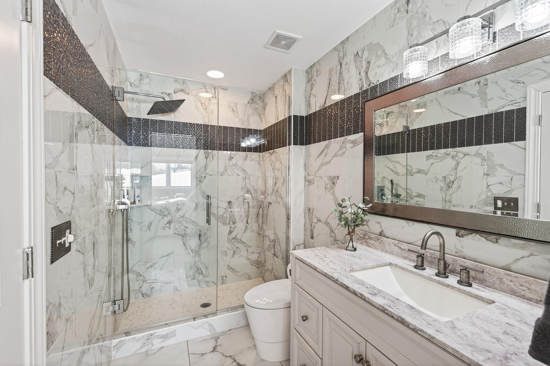 Bedroom five offers access to a walk-through bathroom featuring marble floors and walls, a walk-in shower, and a stylish single vanity.