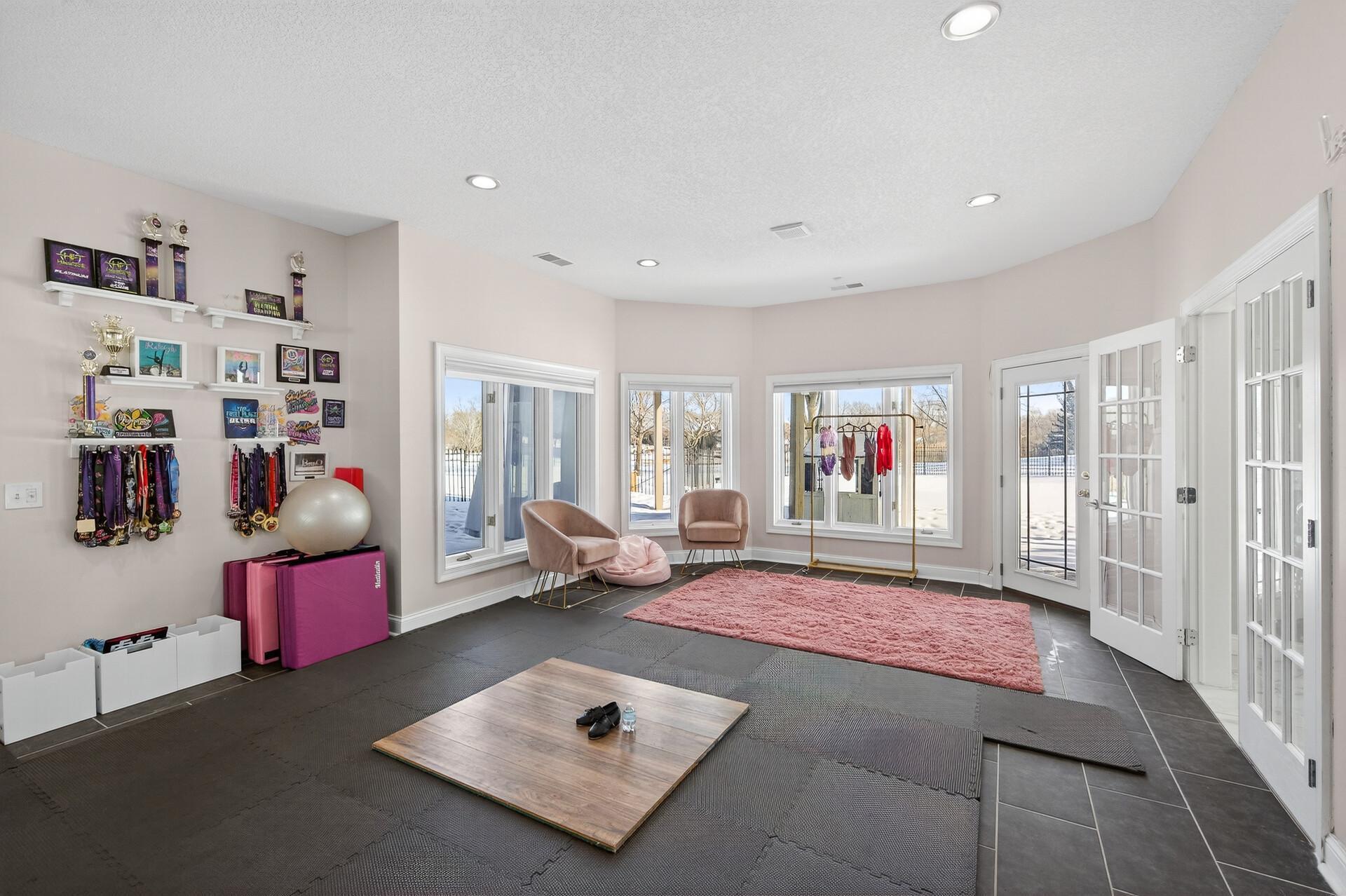 The exercise room is surrounded by large windows, flooding the space with natural light and views of the backyard.