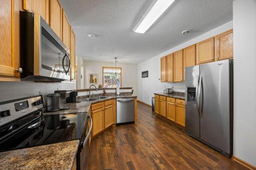 The kitchen is both functional and stylish, featuring stainless steel appliances, under-cabinet lighting, and a two-tier peninsula with breakfast bar seating. Ideal for meal prep or entertaining!