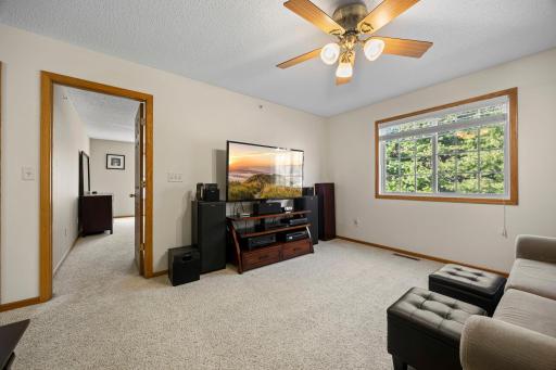 Upstairs, a generously sized den offers flexible living space with soft carpeting, a large window, and a ceiling fan for year-round comfort.