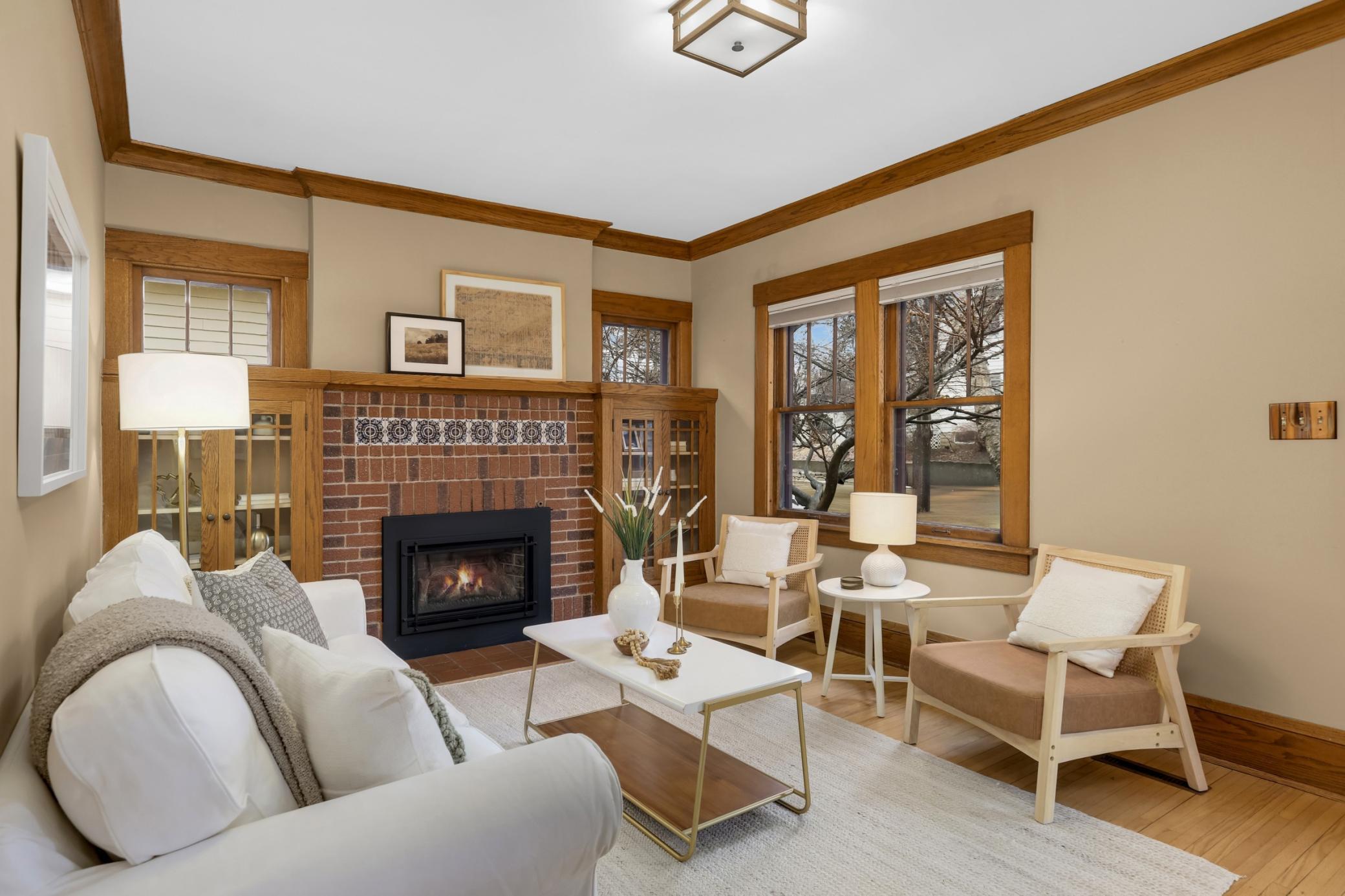 Welcoming living room with tons of light, built in book cases, and gas fireplace