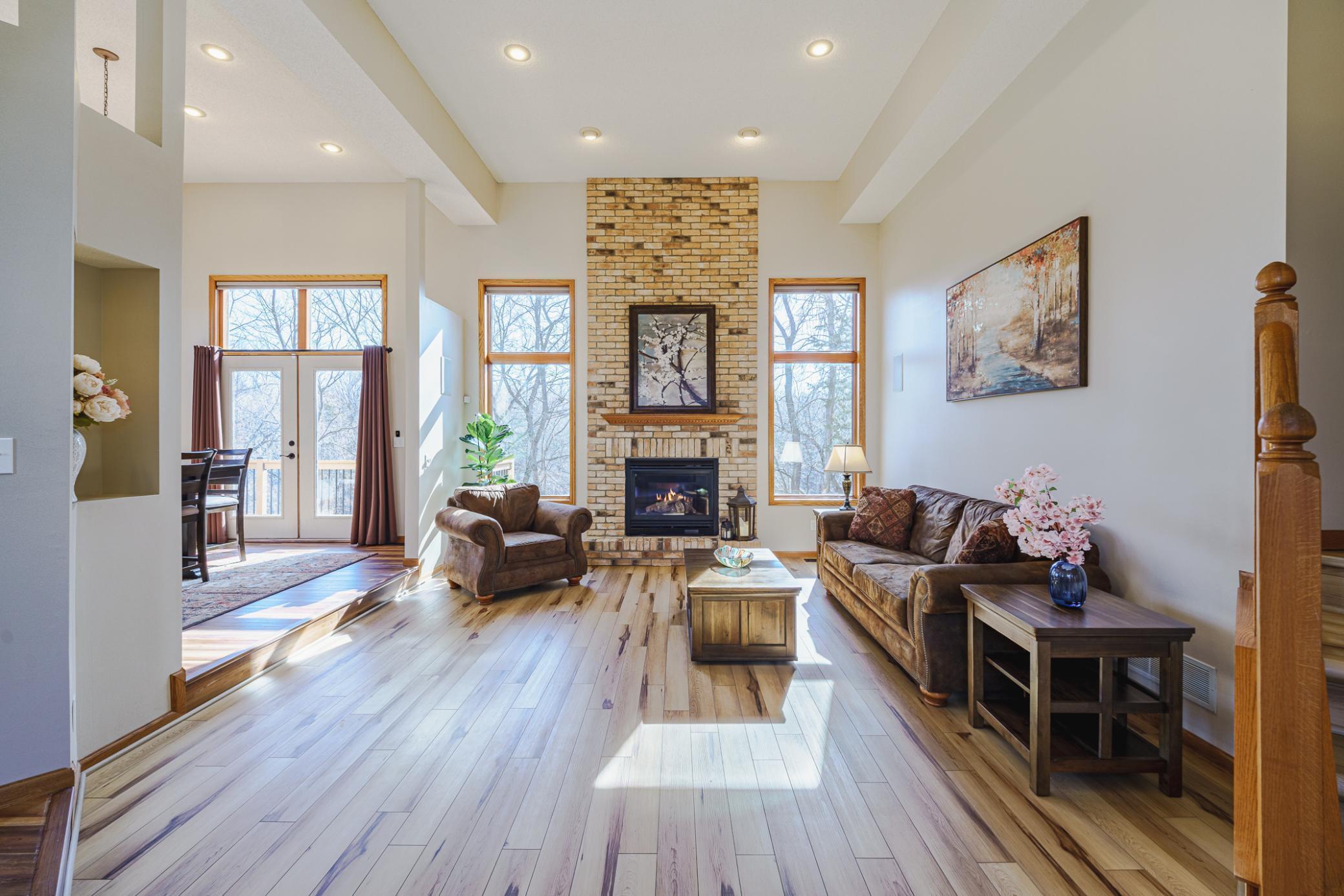 A Great Room with soaring 14-foot ceilings, recessed lighting and a floor-to-ceiling gas fireplace with brick surround is the central focal point of the main level. Transoms above the windows mirror those above the patio door.