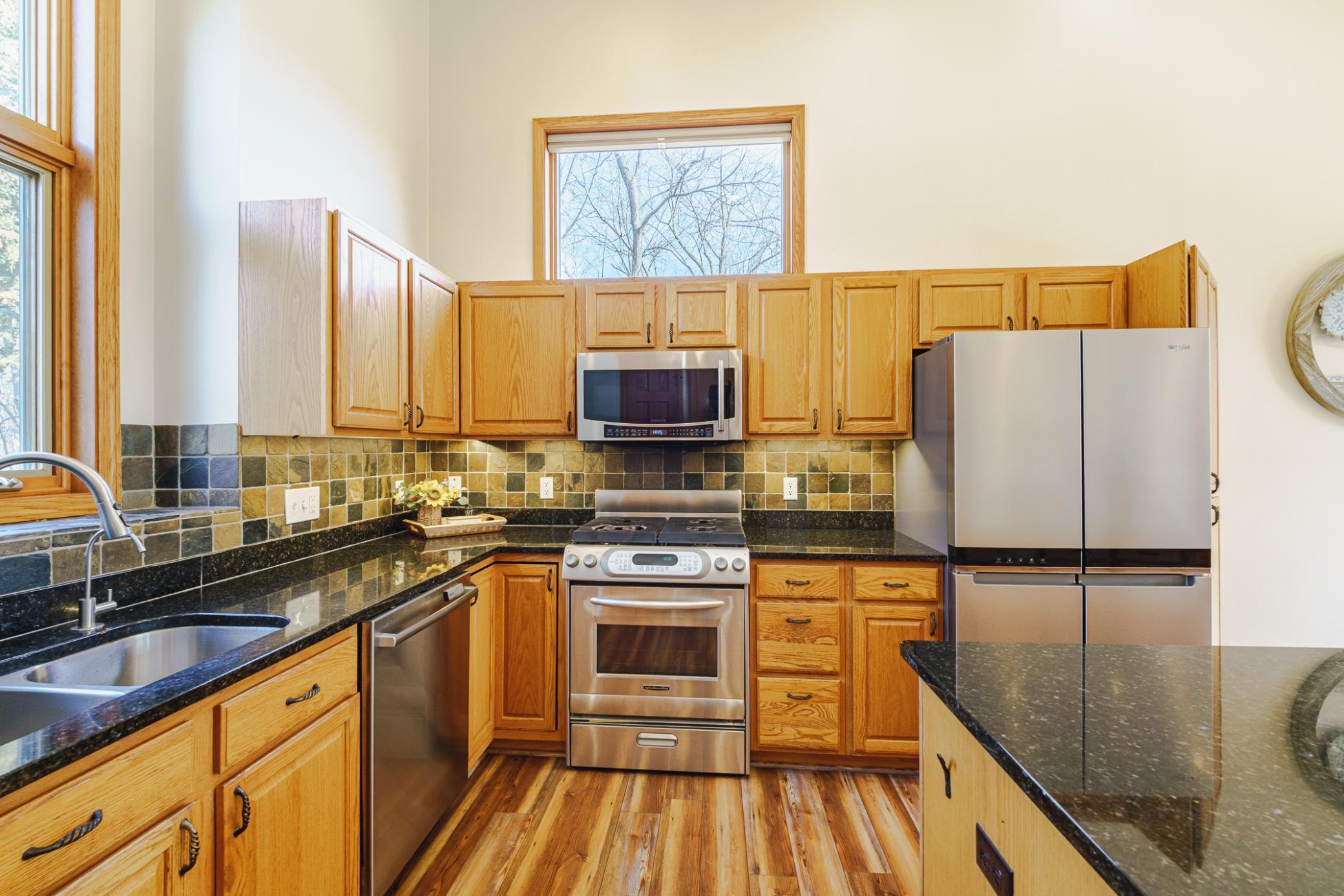 The kitchen receives incredible light, with a large window above the cabinets, and windows above the kitchen sink. The stainless appliances include a gas range and microwave.