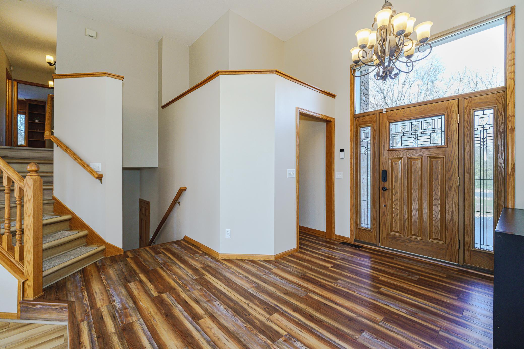 Enter the front door to an open foyer with a large oversized transom above the door, and full-view sidelight windows on either side. There is a mud room to the right, with a boot bench and cubbies.