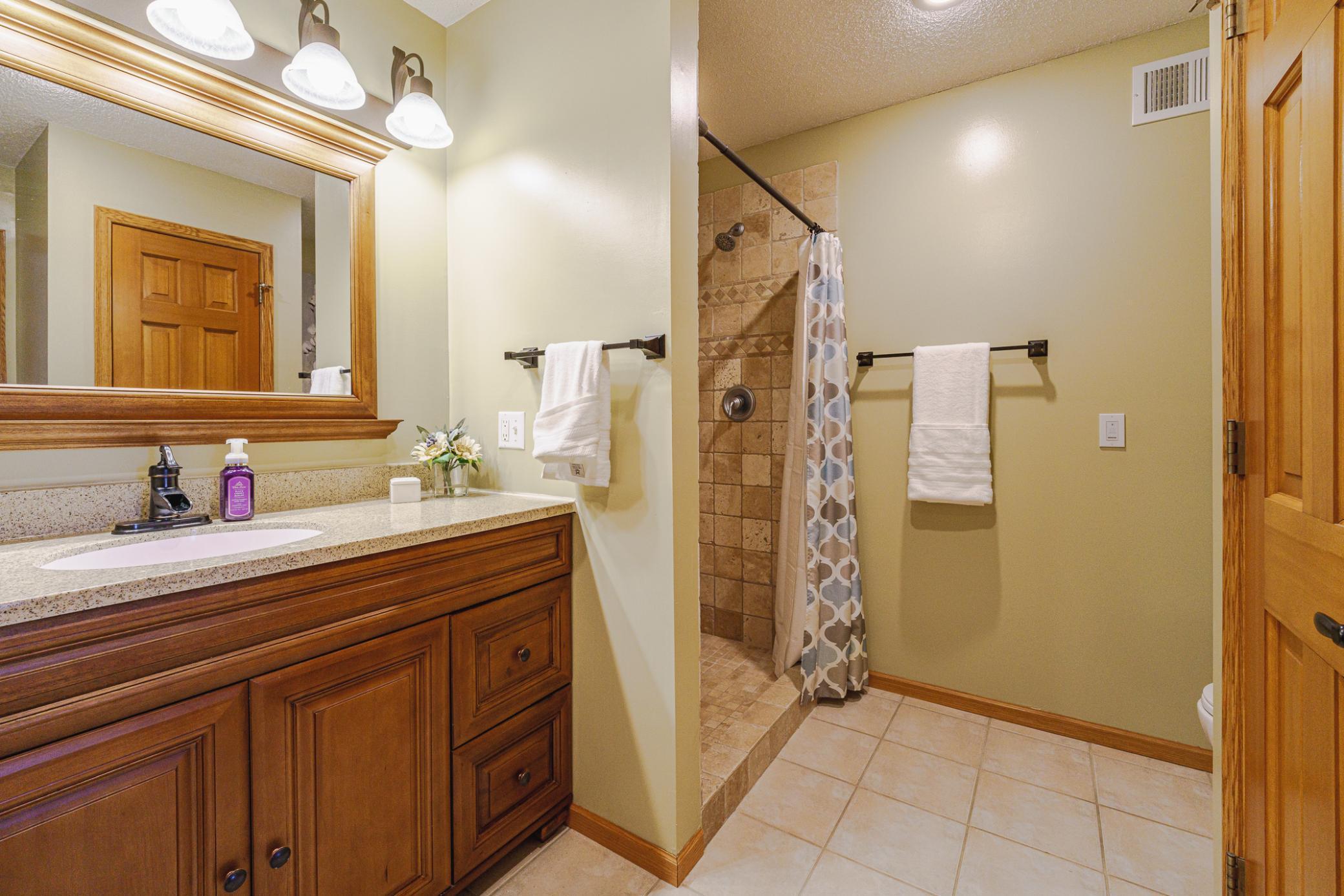 The primary bathroom has a shower with tile surround, and a raised panel vanity with a framed mirror.