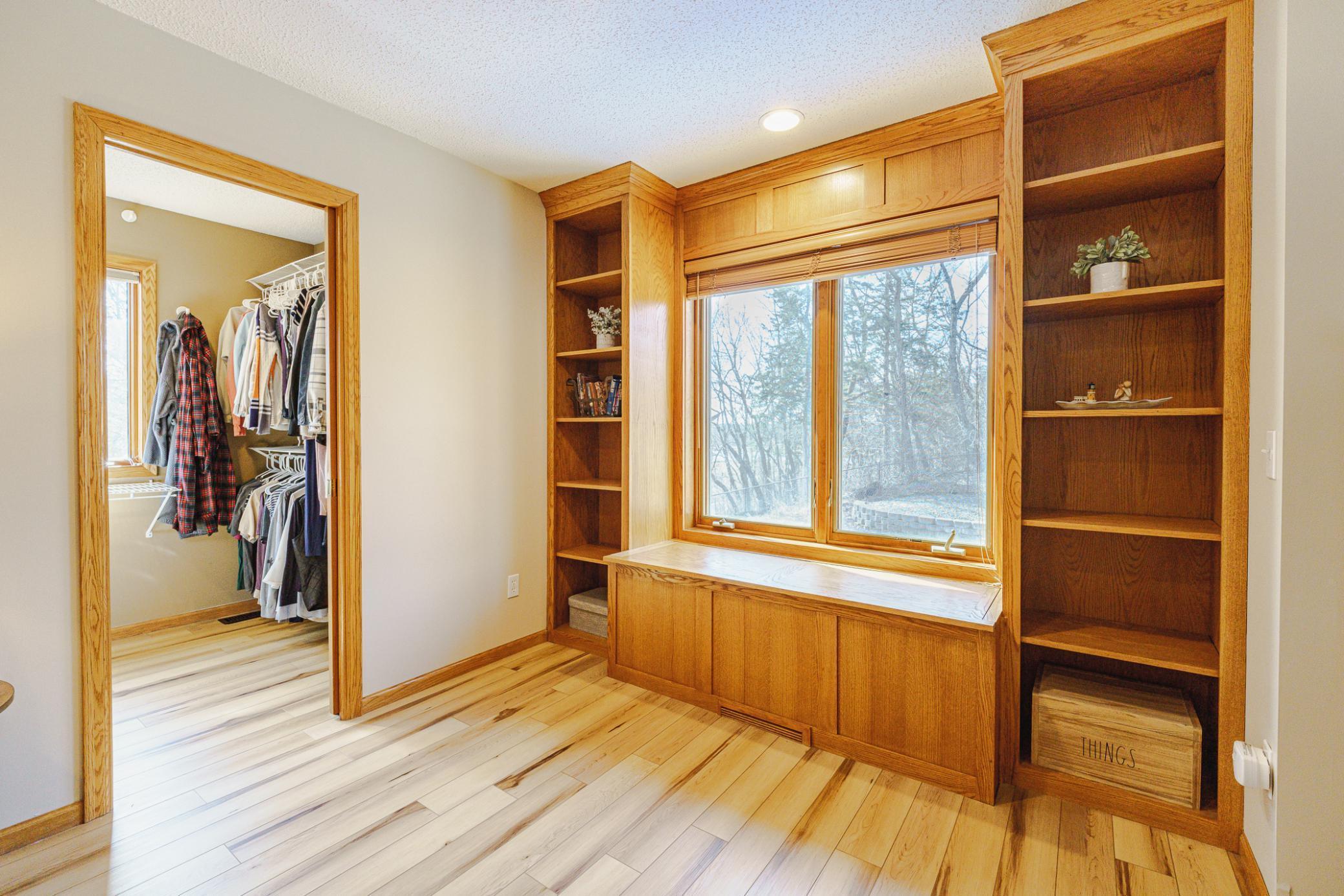 This vaulted bedroom has a built-in window seat flanked by shelves, a ceiling fan and a walk-in closet with a pocket door.