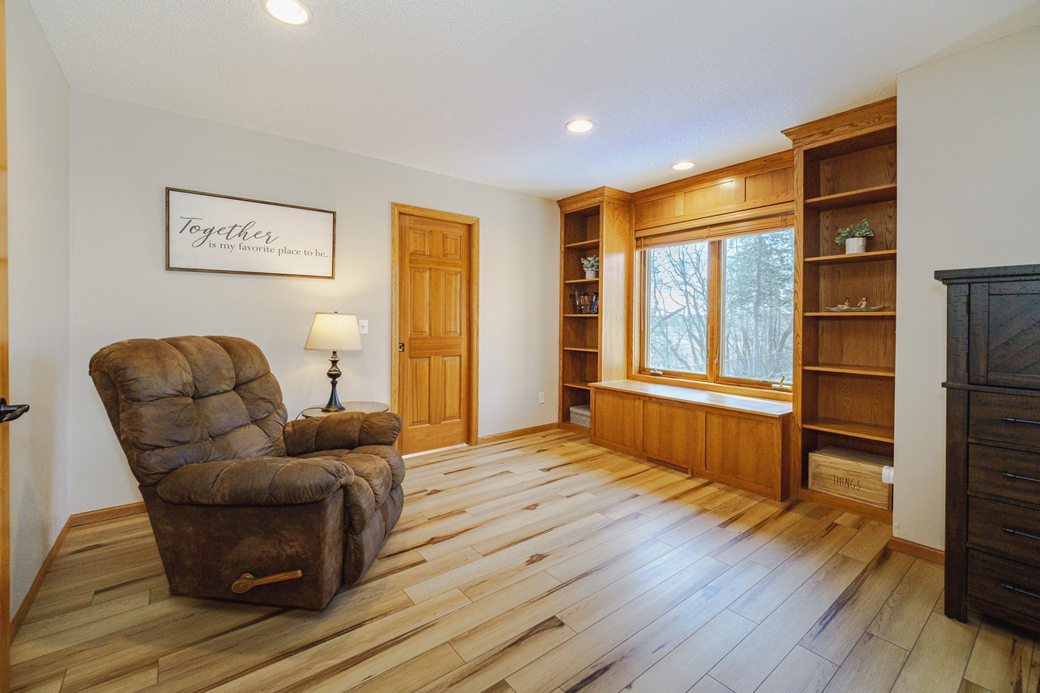 This vaulted bedroom has a built-in window seat flanked by shelves, a ceiling fan and a walk-in closet with a pocket door.