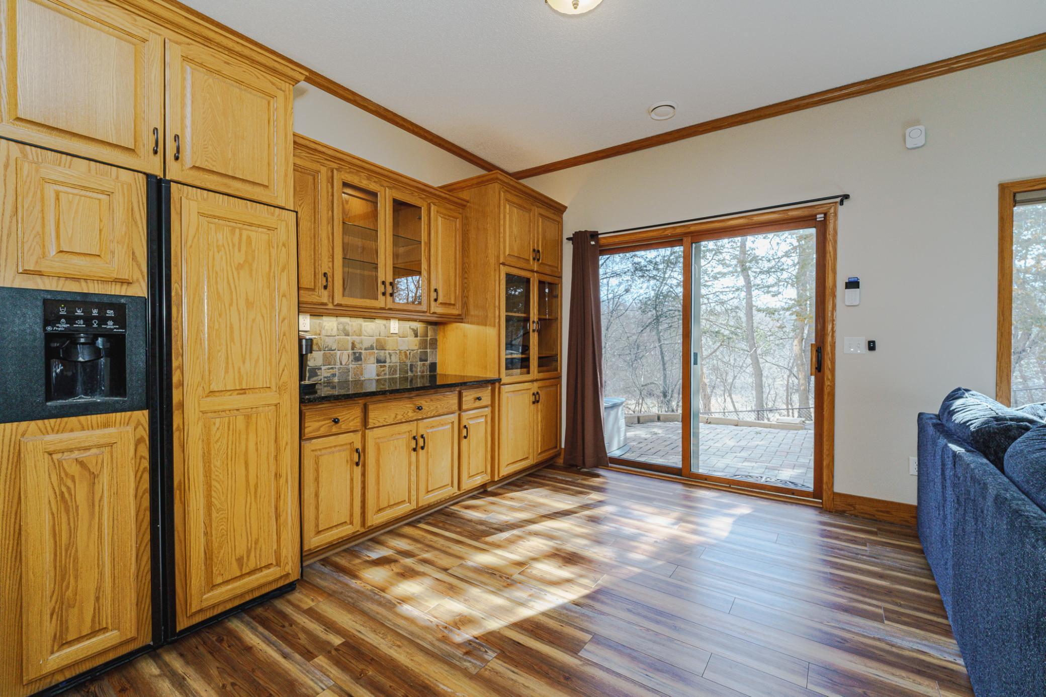 A granite serving bar with a full-sized refrigerator and glass cabinet doors provides easy entertaining options. The family room leads to a paver patio.