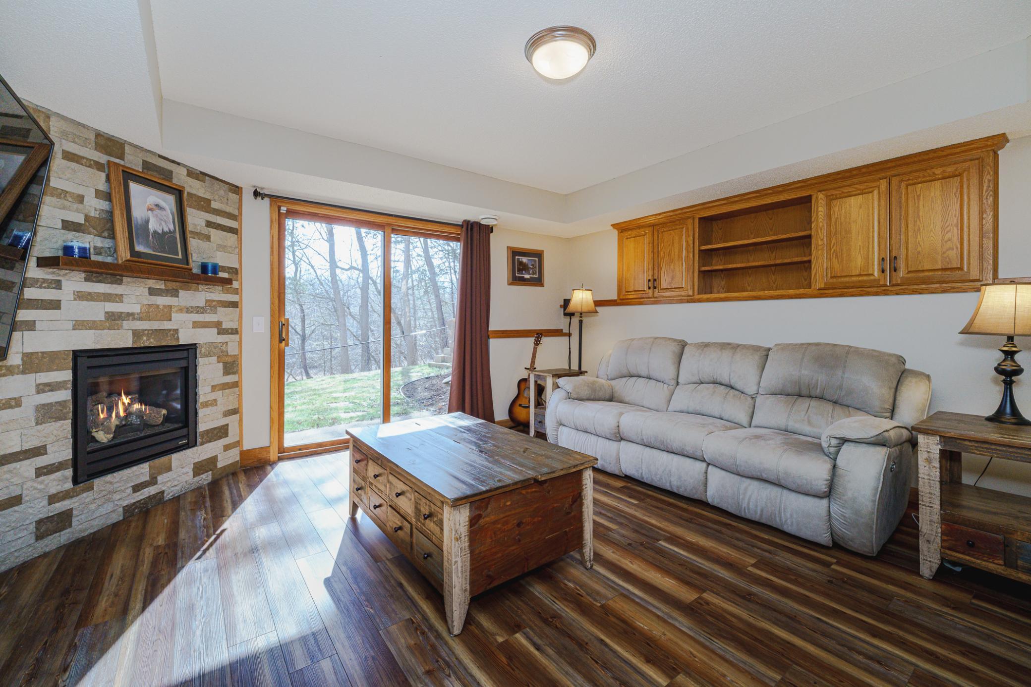 The second lower level has a family room with built-ins along the upper back wall, and a fireplace with stone surround.