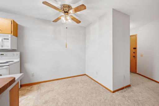Dining area with ceiling fan adjacent to kitchen and main entry.