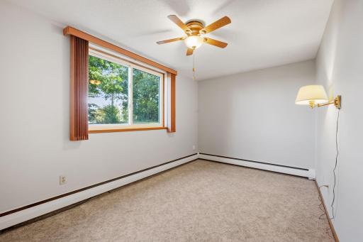 Primary bedroom with large window, ceiling fan, and natural light.