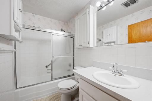 Full bathroom with tub/shower combo and white tile surround.