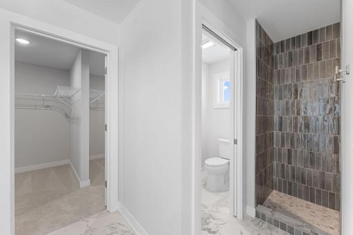 Primary bedroom ensuite with separate dual vanities, fully tiled walk-in shower, freestanding soaker tub and his/hers closet sides