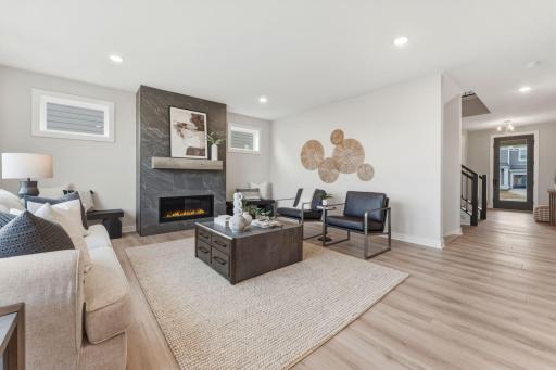 Living room with fully tiled gas fireplace overlooked by kitchen