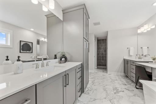 Primary bedroom ensuite with separate dual vanities, fully tiled walk-in shower, freestanding soaker tub and his/hers closet sides