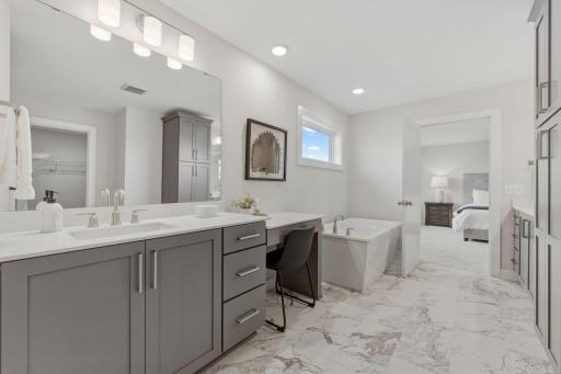 Primary bedroom ensuite with separate dual vanities, fully tiled walk-in shower, freestanding soaker tub and his/hers closet sides