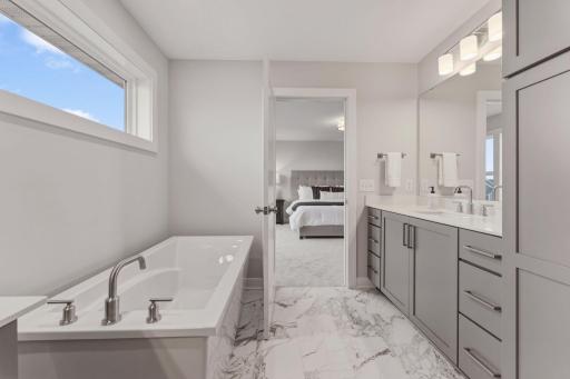 Primary bedroom ensuite with separate dual vanities, fully tiled walk-in shower, freestanding soaker tub and his/hers closet sides