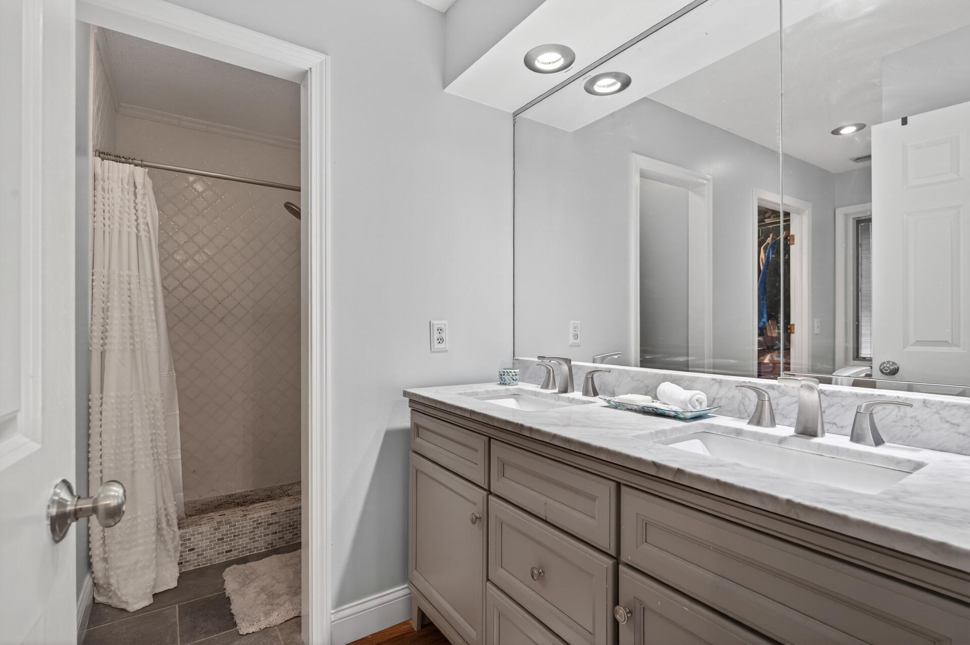 Primary bath with walk-in tile shower and double vanity.