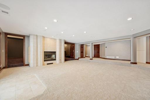 The lower-level family room offers a cozy wood-burning fireplace, freshly painted walls, and luxurious new carpet.