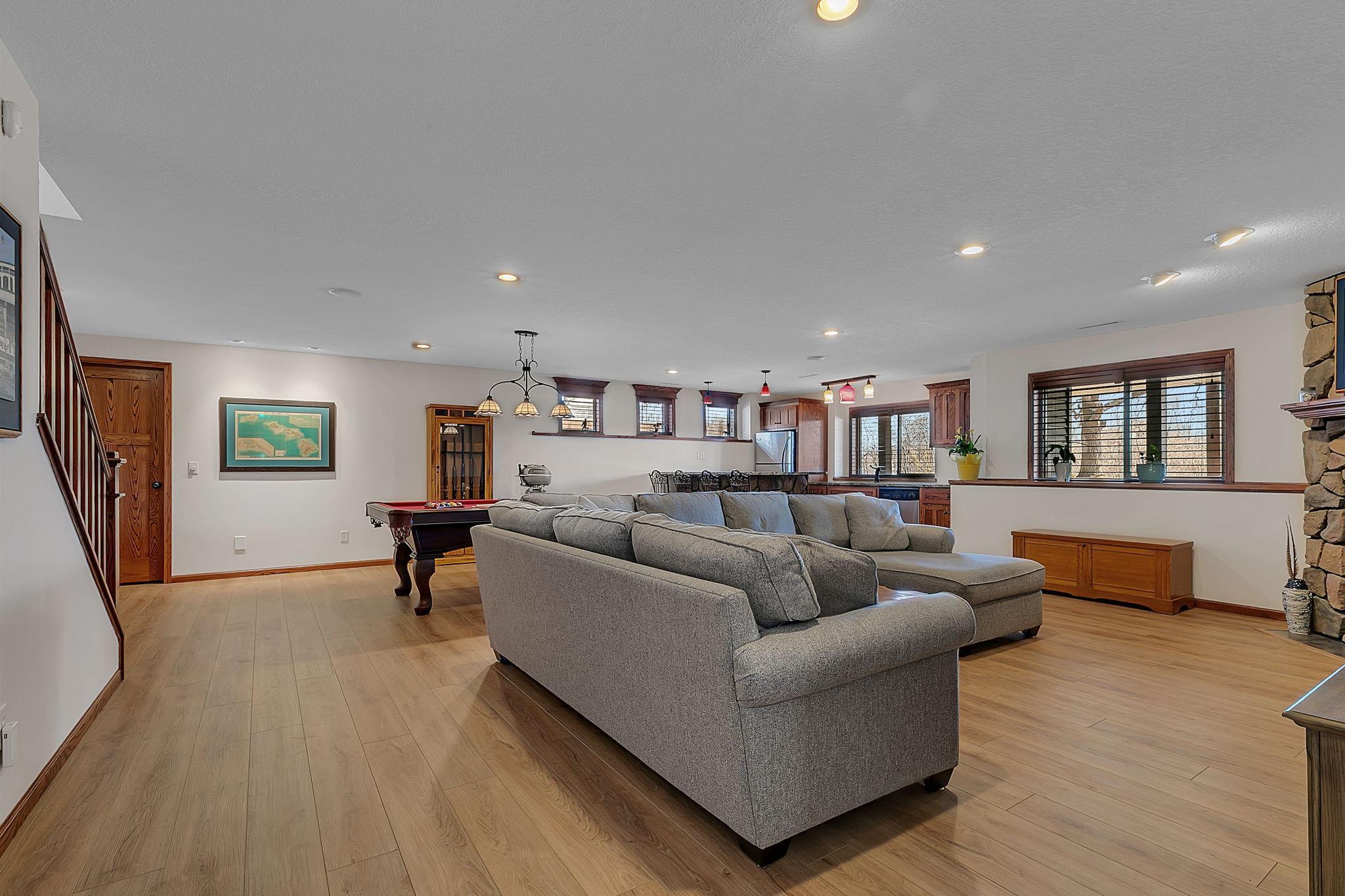 A second view showcasing the spacious lower-level living room, highlighted by a stylish bar area and inviting game space.
