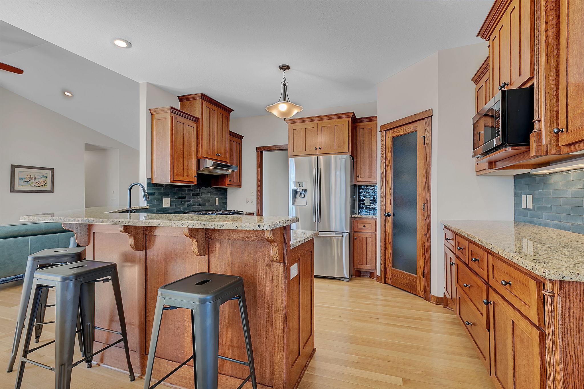 This kitchen features ample cabinet storage, stainless steel appliances, a walk-in pantry, a two-tier peninsula, beautiful granite countertops, and a stylish tile backsplash—perfect for both cooking and entertaining.