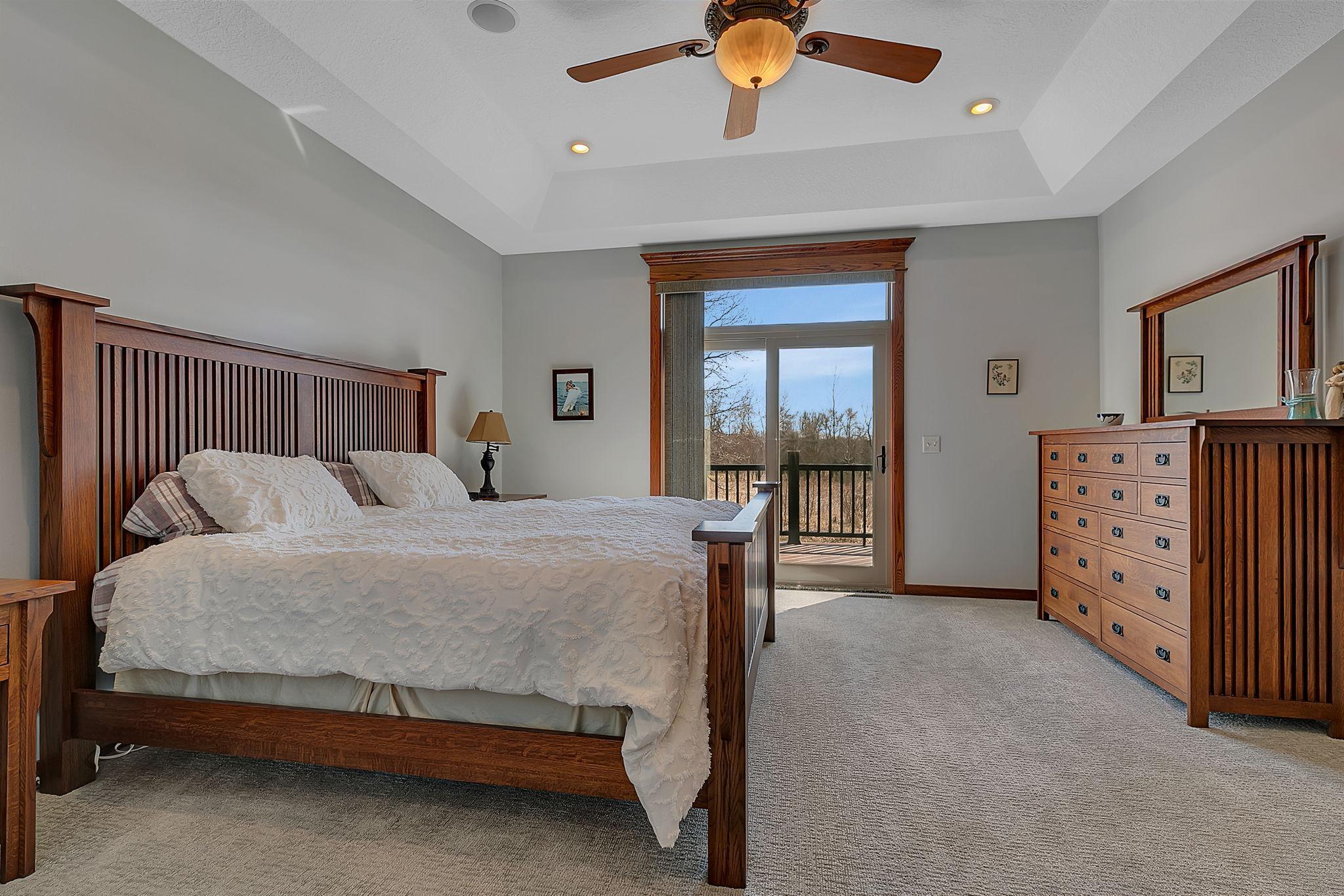 Spacious and airy, the primary bedroom boasts a vaulted ceiling, ceiling fan, private ensuite, and convenient access to the deck.