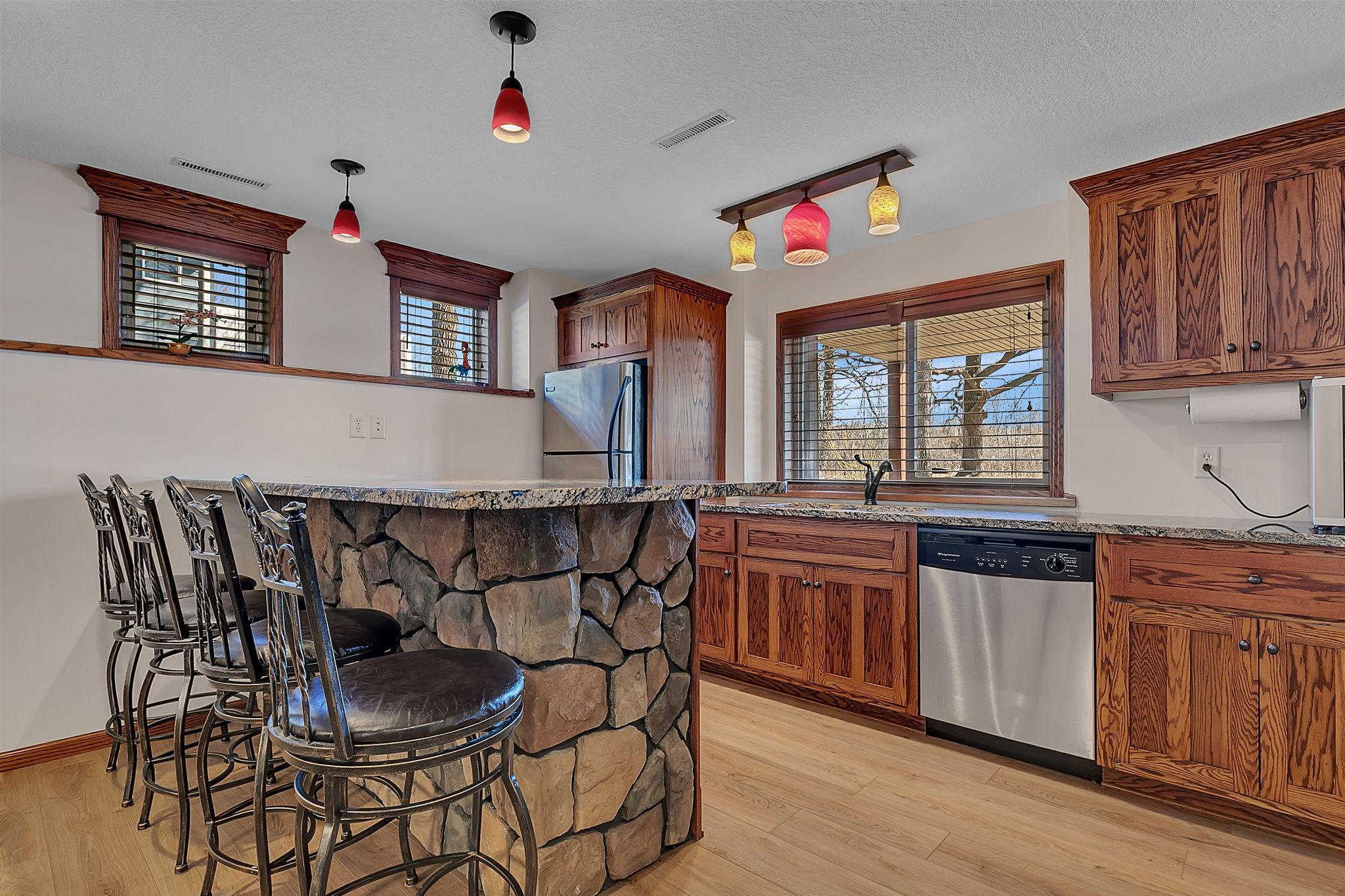 Stylish wet bar featuring a fridge, sink, dishwasher, and ample countertop seating. Perfect for entertaining guests or enjoying casual gatherings.