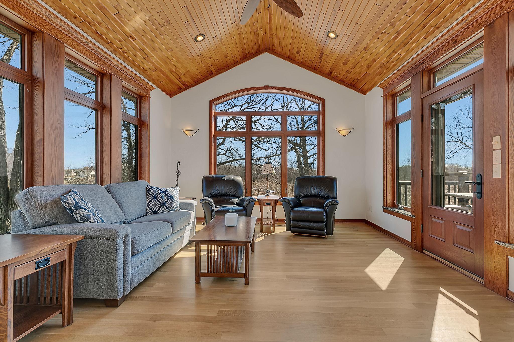 Another angle of the sunroom highlights its expansive wall of windows, filling the space with natural light and offering beautiful outdoor views, along with direct access to the deck for easy indoor-outdoor living.
