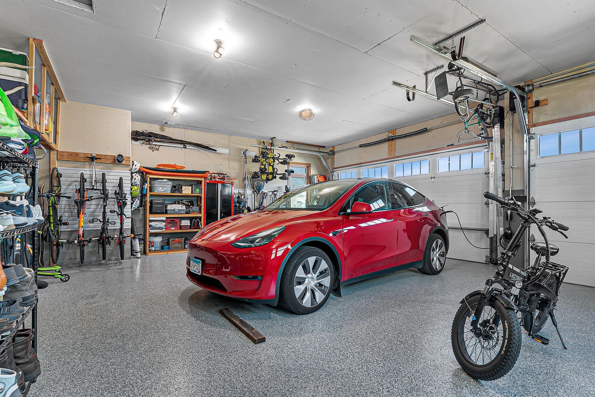 Spacious garage featuring durable epoxy flooring, built-in shelving for organized storage, and an electric vehicle charging station for modern convenience.