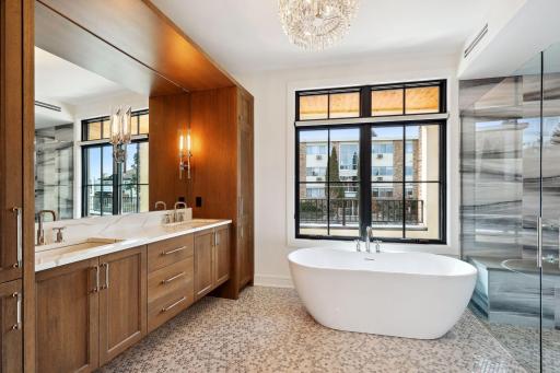 Spa-like primary bath with heated floors, dual vanity areas, large soaker tub, and curb-less walk-in shower